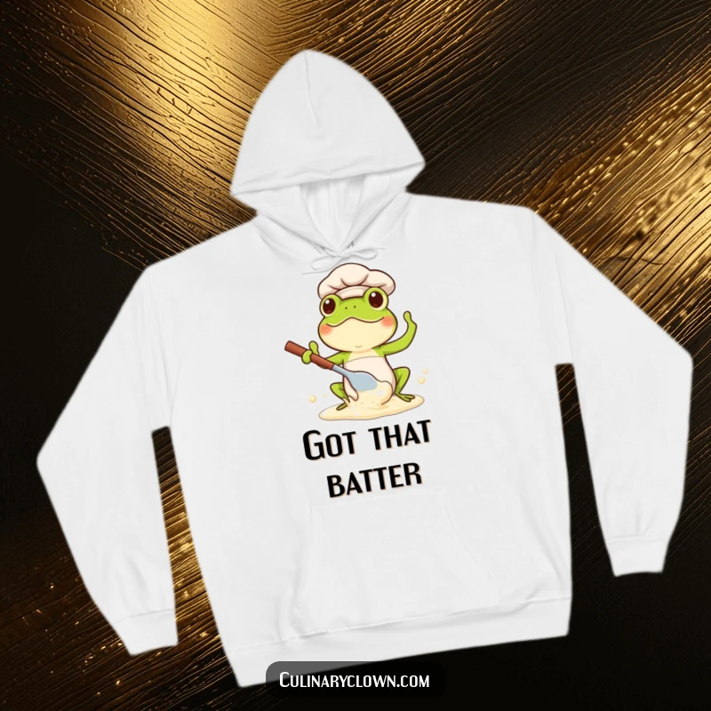 Funny Kawaii Frog Chef Hoodie: Cute frog chef energetically splashing batter, embodying joyful kitchen chaos.